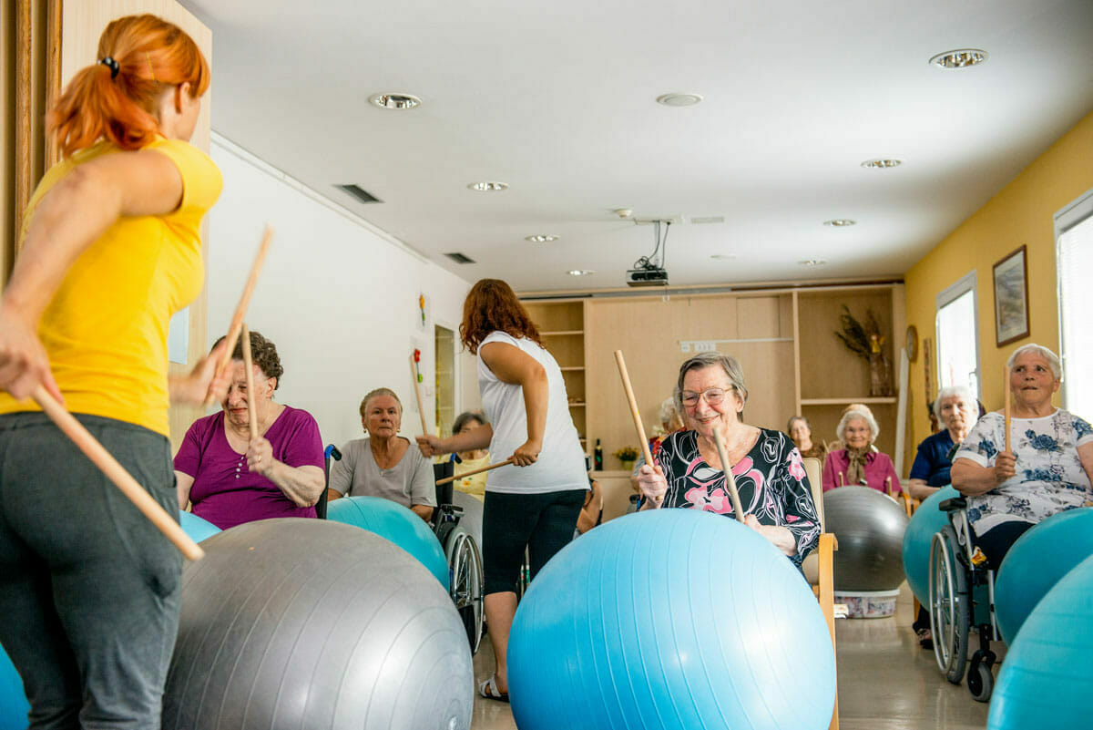 Scheduled Activities For Fun Seniors staying active with an interactive music class with exercise balls and drum sticks