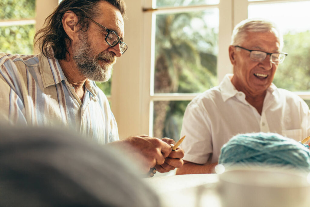 Senior Beard Man Knitting With Friend Sitting By Senior Bearded Man Knitting With Friend Sitting By