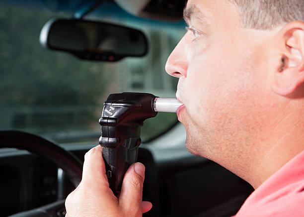 A male driver is blowing into an ignition interlock system